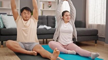 Erkek ve kadın çift evde yoga egzersizi yapıyor.