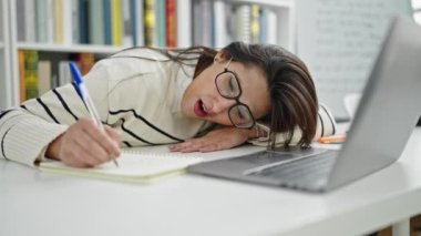 Genç, güzel İspanyol bir öğrenci kütüphanede notlar yazıyor.