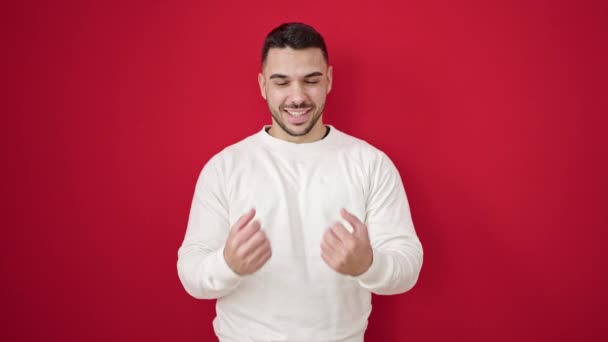 Jonge Spaanse Man Glimlachend Zelfverzekerd Staan Met Winnaarsuitdrukking Geïsoleerde Rode — Stockvideo