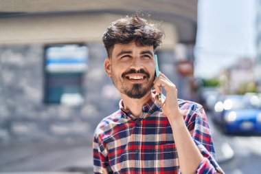 Genç İspanyol adam gülümsüyor. Kendine güveniyor. Sokakta akıllı telefondan konuşuyor.