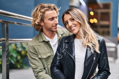 Kadın ve erkek gülümsüyor. Kendilerine güveniyorlar. Sokakta sarılıyorlar.