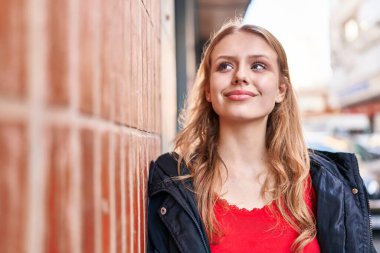 Young blonde woman smiling confident looking to the side at street