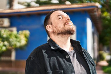 Genç İspanyol adam gülümsüyor. Parkta nefes alıyor.