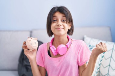 Kumbarayı tutan genç kız gururla bağırıyor zaferi kutluyor ve başarıyı kollarını kaldırarak kutluyor. 