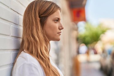 Young blonde girl with relaxed expression standing at street
