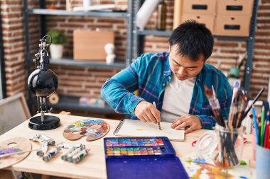 Young chinese man artist drawing on notebook at art studio