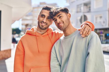 İki erkek caddede birbirlerine sarılıyorlar.