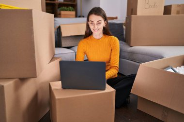 Young caucasian woman using laptop sitting on floor at new home