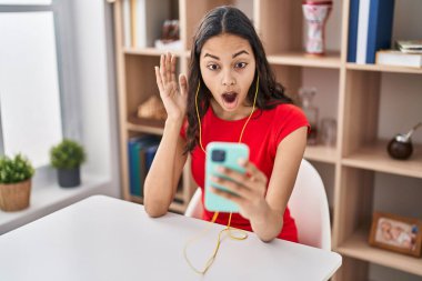 Genç Brezilyalı bir kadın akıllı telefonuyla video görüşmesi yapıyor. Şaşırtmak için ağzı açık kalmış, korkmuş ve hayrete düşmüş. 