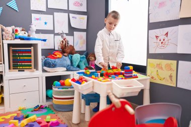 Beyaz çocuk anaokulunda inşaat bloklarıyla oynuyor.