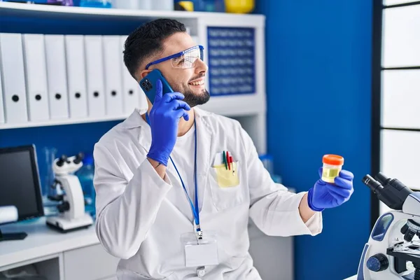 Young Arab Man Scientist Talking Smartphone Holding Urine Test Tube — стоковое фото