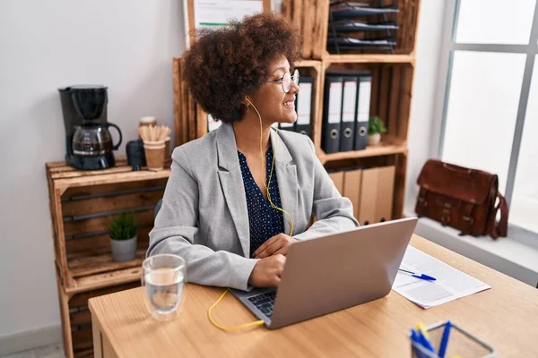 使用笔记本电脑和耳机在办公室工作的非洲裔美国女商人 — 图库照片