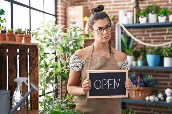 stock image Hispanic woman working at florist holding open sign skeptic and nervous, frowning upset because of problem. negative person. 