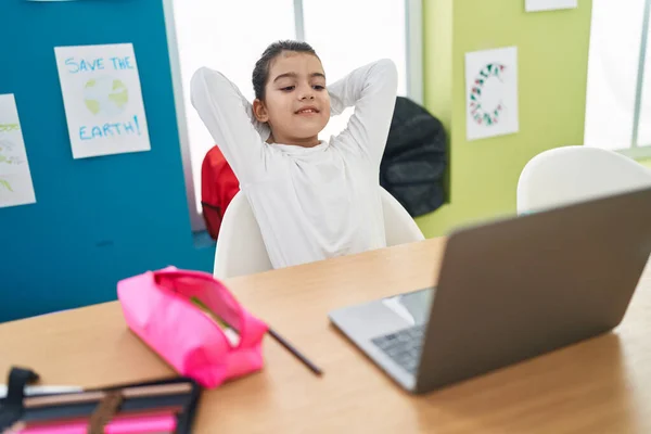 教室で頭の上で手でリラックスしたラップトップを使用して愛らしいヒスパニック系の女の子学生 — ストック写真