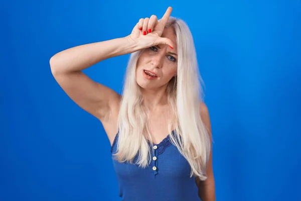 Mulher Caucasiana Sobre Fundo Azul Zombando Pessoas Com Dedos Testa — Fotografia de Stock