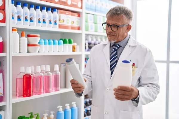 Middle Age Grey Haired Man Pharmacist Holding Shampoo Bottles Laboratory — Stock Photo, Image