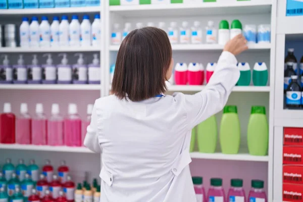 薬局で棚に製品を保持する中年女性薬剤師 — ストック写真