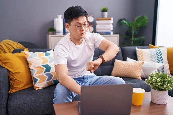 Young Asian Man Using Laptop Home Sitting Sofa Looking Watch — Stock Photo, Image