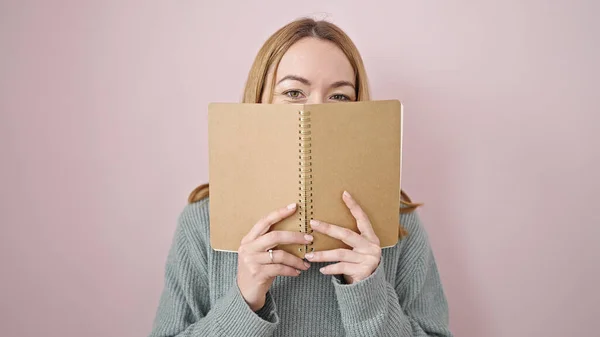 Giovane Donna Bionda Che Copre Viso Con Libro Sfondo Rosa — Foto Stock