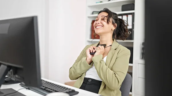 オフィスで勝者のジェスチャーでコンピュータやスマートフォンを使用して若い美しいヒスパニック系女性のビジネスワーカー — ストック写真
