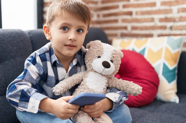 Schattige Kaukasische Jongen Knuffelen Teddybeer Met Behulp Van Smartphone Thuis — Stockfoto
