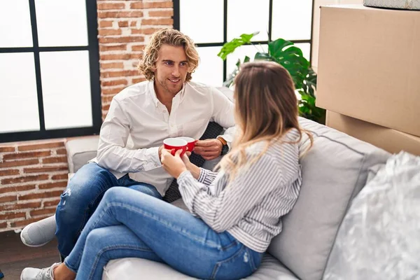 男と女カップル飲むコーヒー座っています上のソファに新しい家 — ストック写真