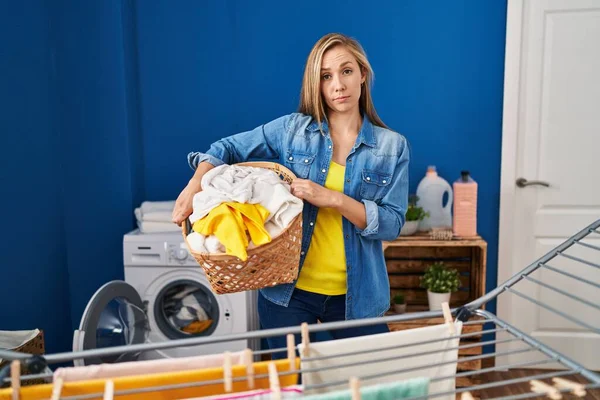 Young Blonde Woman Holding Laundry Basket Skeptic Nervous Frowning Upset — Stock Photo, Image