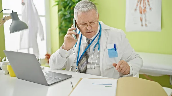 Μεσήλικας Γκριζομάλλης Γιατρός Μιλάει Στο Smartphone Διαβάζοντας Ιατρική Έκθεση Στην — Φωτογραφία Αρχείου