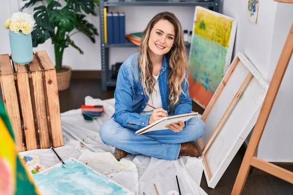 若い女性アーティストドローイングノートブックの上に座っているアートスタジオ — ストック写真