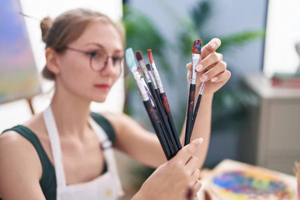 年轻的高加索女艺术家在艺术工作室拿着画笔 — 图库照片