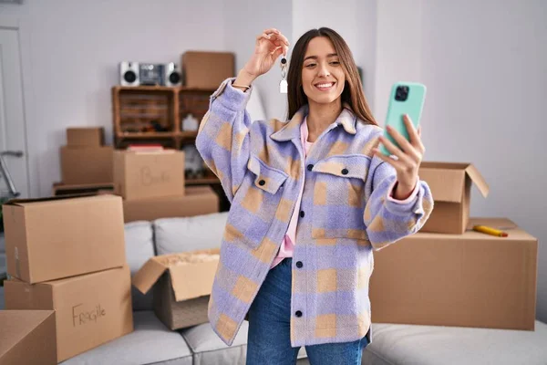 Stock image Young beautiful hispanic woman having video call holding key at new home