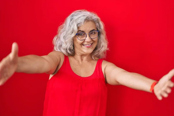 Kırmızı Arka Planda Gri Saçlı Orta Yaşlı Bir Kadın Kucaklanmak — Stok fotoğraf