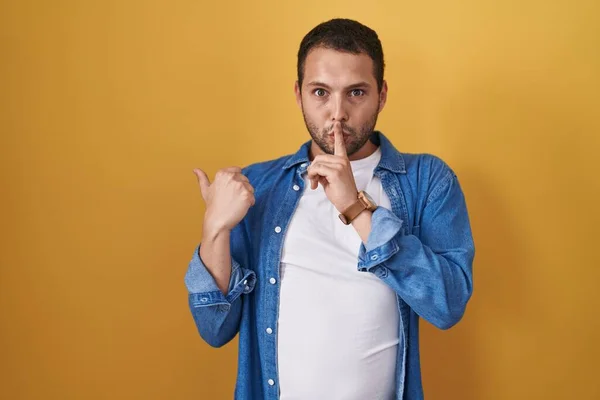 Hispanic Man Standing Yellow Background Asking Quiet Finger Lips Pointing — Stockfoto