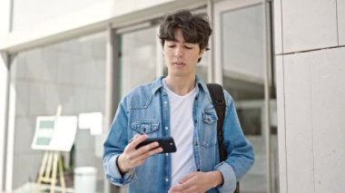 Genç İspanyol asıllı kendine güvenen öğrenci üniversitede akıllı telefondan selfie çekiyor.