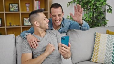 İki erkek birbirlerine sarılıp video görüşmesi yapıyorlar.