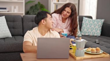 Kadın ve erkek kahvaltıyı evde dizüstü bilgisayarla yapıyorlar.