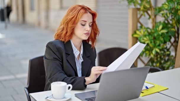 コーヒーショップのテラスでノートパソコン読み取り文書を使用して若い赤毛の女性のビジネスワーカー — ストック動画