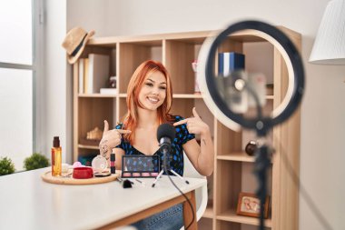 Makyaj yapmak için makyaj yapan beyaz bir kadın. Kendine güvenen, gülümseyen, kendini gururlu ve mutlu gösteren bir kadın.. 