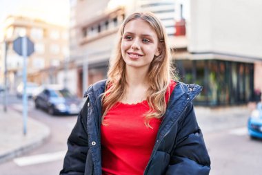 Young blonde woman smiling confident looking to the side at street