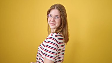 Young blonde woman smiling confident standing over isolated yellow background