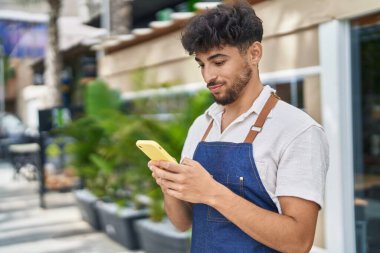 Young arab man waiter using smartphone working at restaurant