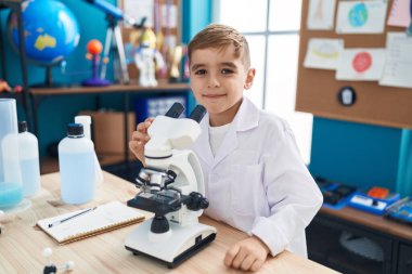 Adorable hispanic boy student smiling confident using microscope at laboratory classroom