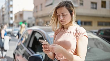 Sokakta duran akıllı telefonu kullanan genç sarışın kadın.