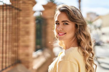 Sokakta kendinden emin gülümseyen genç bir kadın