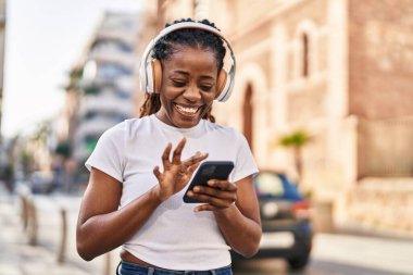 African american woman listening to music standing at street