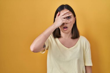 İspanyol kız sarı arka planda rahat bir tişört giyiyordu. Şoka girip yüzünü ve gözlerini kapatıyordu. Utanmış bir ifadeyle parmaklarının arasından bakıyordu.. 