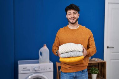 Sakallı, sakallı, katlanmış kirli çamaşırları olan İspanyol bir adam çılgın bir kutlama yapıyor ve gözleri açık heyecanla haykırıyor.. 