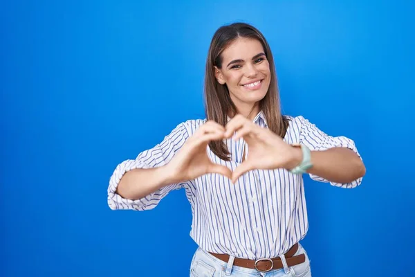 Spaanse Jonge Vrouw Staat Blauwe Achtergrond Glimlachend Liefde Doen Hart — Stockfoto