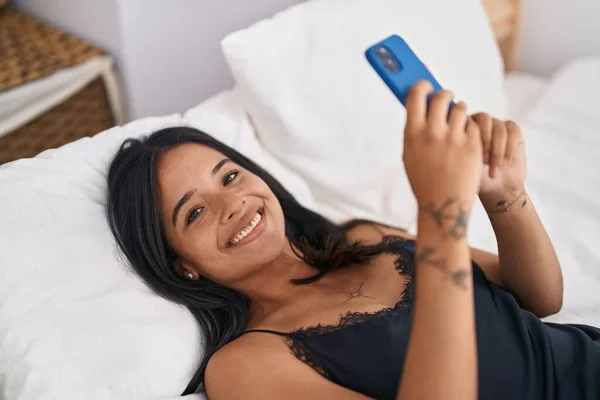 Young Hispanic Woman Using Smartphone Lying Bed Bedroom — Foto de Stock