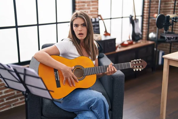 Junge Schöne Frau Spielt Klassische Gitarre Musikstudio Verängstigt Und Erstaunt — Stockfoto
